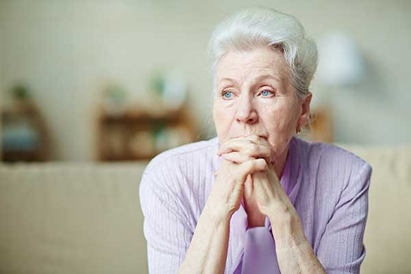 annuity death benefit worried older woman senior in lavender shirt with white hair