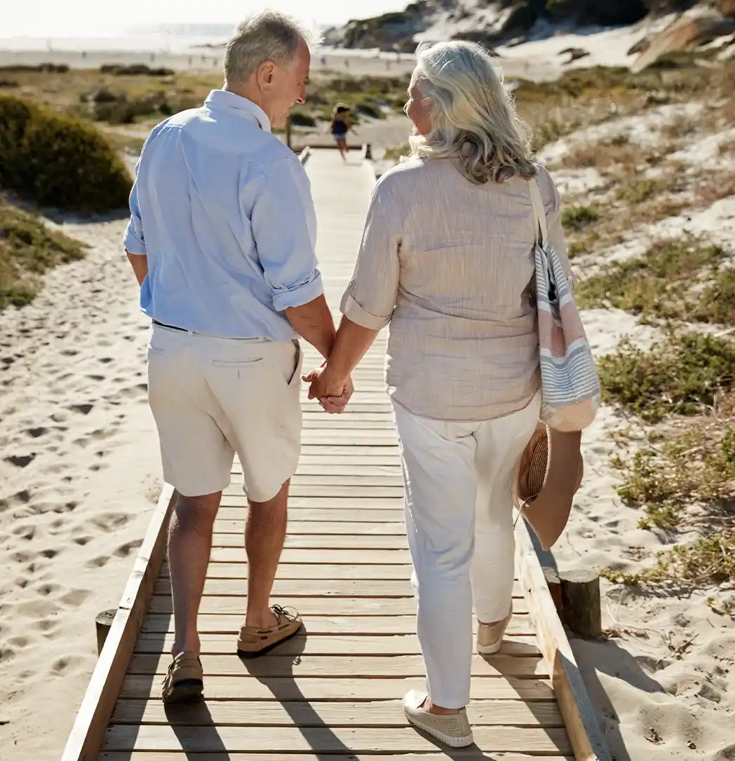 portrait of couple walking on wooden path toward the beach guaranteed income